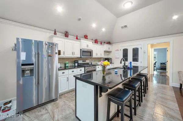 a kitchen with kitchen island a counter top space cabinets stainless steel appliances and a dining table