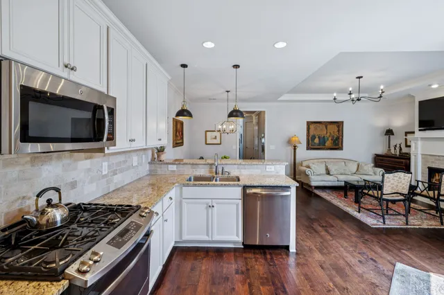 a kitchen with stainless steel appliances granite countertop a stove a sink dishwasher and a microwave with wooden floor