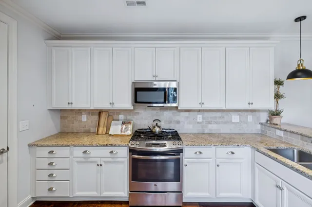 a kitchen with granite countertop white cabinets and stainless steel appliances