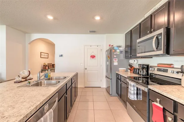 a kitchen with stainless steel appliances granite countertop a refrigerator a stove and a sink with wooden floor