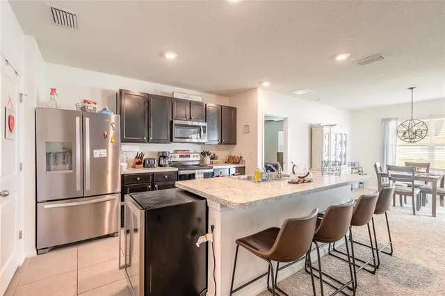 a kitchen with refrigerator a sink and chairs