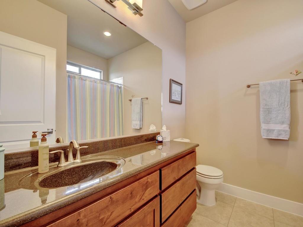 4545 Mattie Street Austin, TX 78723 - Photo 25 of 28 a bathroom with a granite countertop sink a toilet and mirror