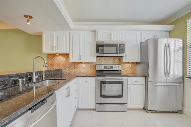 a kitchen with refrigerator a stove a sink and cabinets