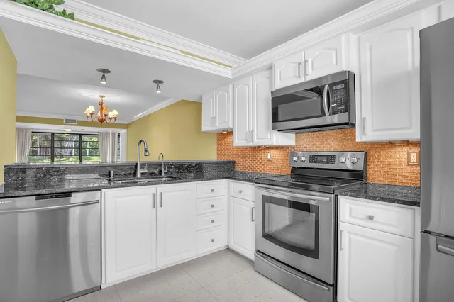 a kitchen with granite countertop white cabinets white stainless steel appliances and a sink
