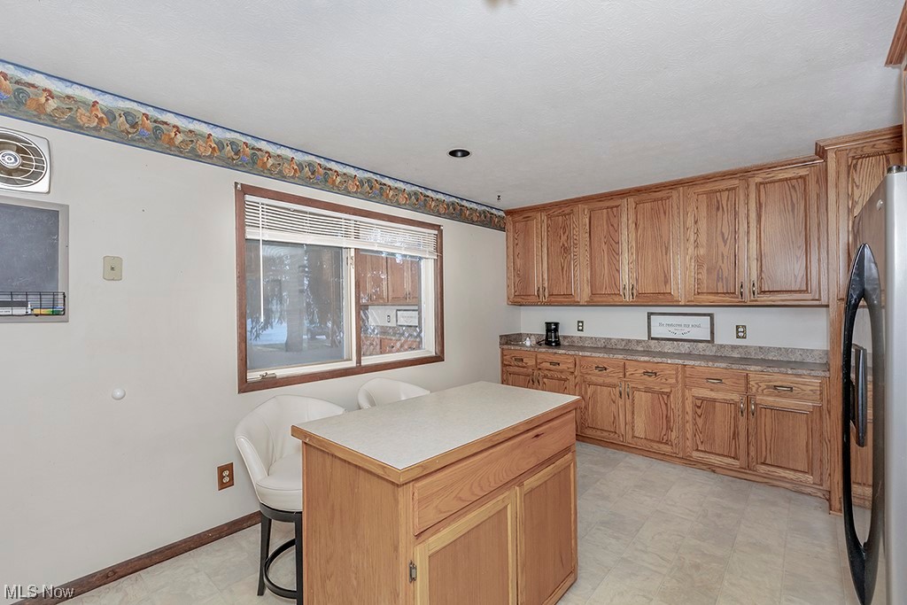 39102 Chestnut Ridge Road Elyria, OH 44035 - Photo 12 of 44 Kitchen featuring refrigerator, a center island, light tile flooring, and a breakfast bar