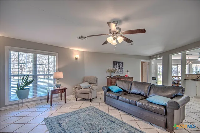a living room with furniture a large window and a dining table