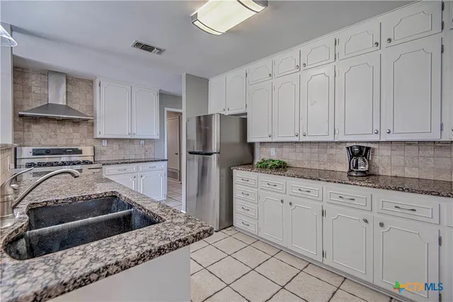 a kitchen with granite countertop a sink stove and refrigerator