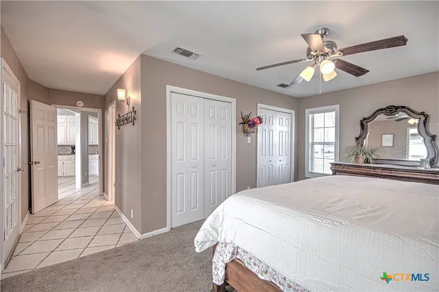 a bedroom with a bed and a large mirror with a ceiling fan