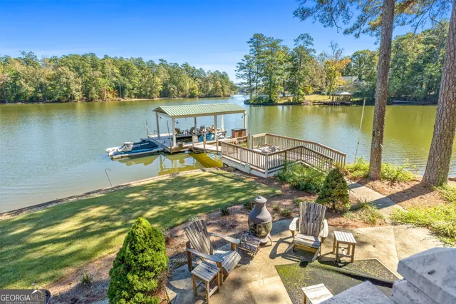 a view of a chairs and table on wooden deck with lake view