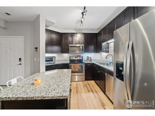 a kitchen with stainless steel appliances granite countertop a refrigerator a stove and a sink
