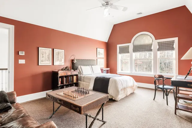 a spacious bedroom with a bed a table with chair and window