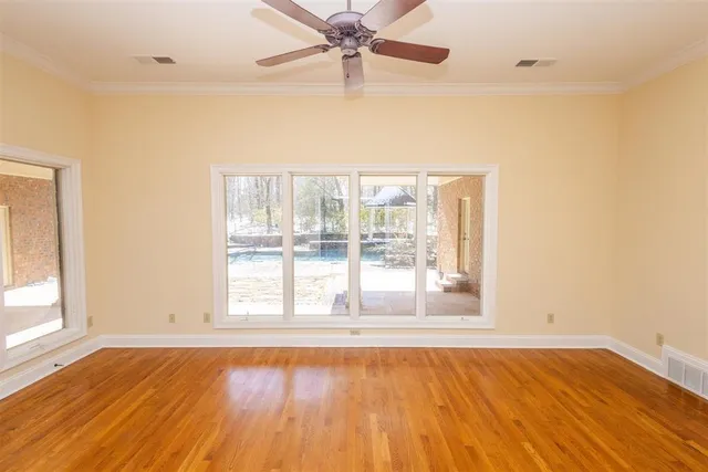an empty room with wooden floor and windows