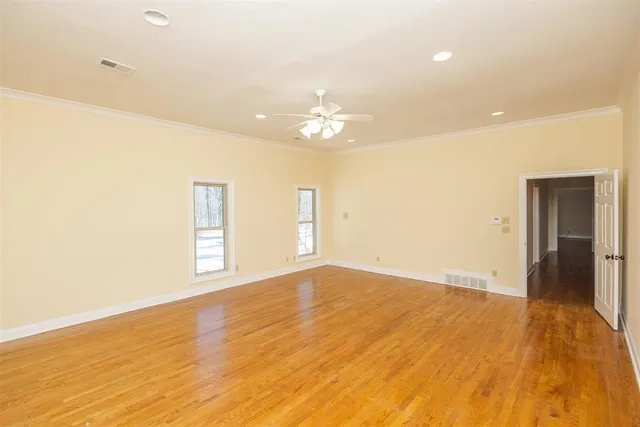 a view of empty room with wooden floor and fan