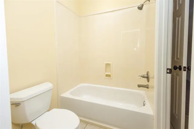 a white toilet sitting next to a bath tub