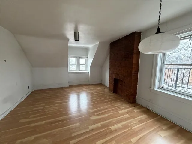 an empty room with wooden floor windows and fireplace