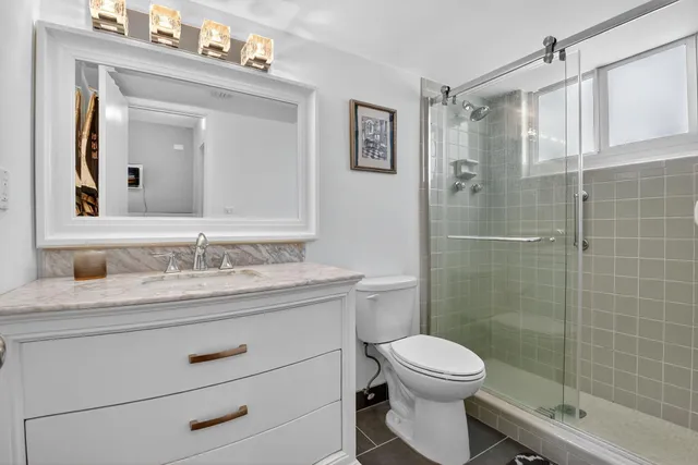 a bathroom with a granite countertop sink toilet a mirror a vanity and shower