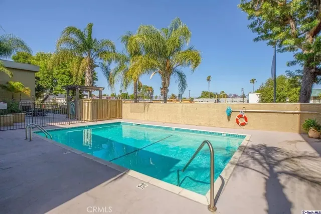 a view of swimming pool with a yard and palm trees