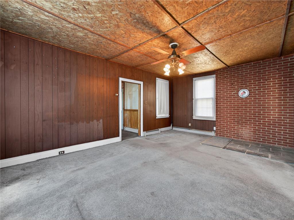 15845 Kutztown Road Mertztown, PA 19539 - Photo 6 of 24 A well-lit room offers cozy wood paneling and a brick accent wall with a classic ceiling fan.