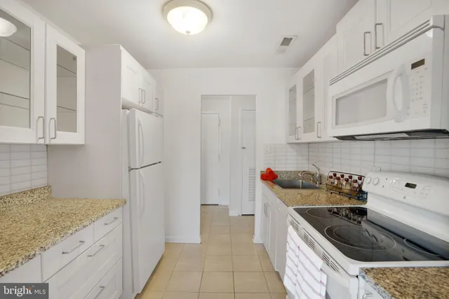 a kitchen with stainless steel appliances granite countertop white cabinets and white appliances
