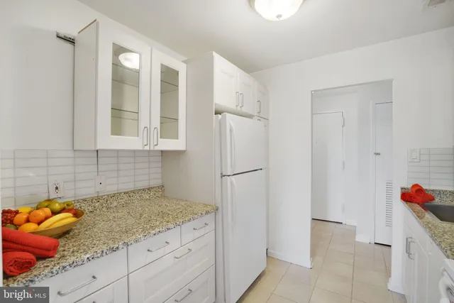 a kitchen with granite countertop a stove a sink and a refrigerator with white cabinets