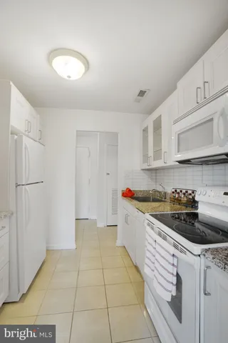 a kitchen with granite countertop a sink a stove and cabinets