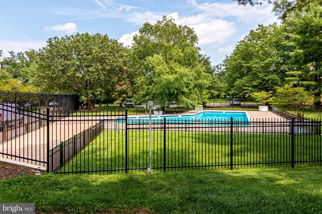 swimming pool view with a seating space and trees in the background