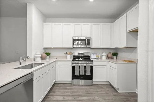 a kitchen with stainless steel appliances granite countertop a stove top oven a sink and dishwasher with white cabinets