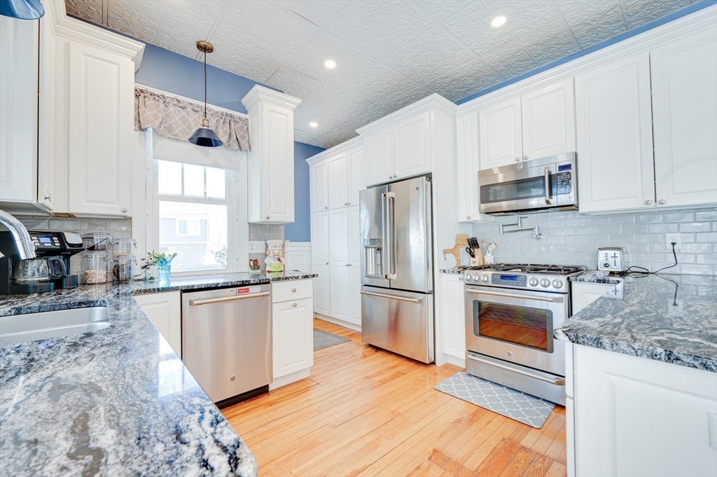 23 Germain Street Worcester, MA 01602 - Photo 12 of 42 a kitchen with granite countertop a refrigerator a sink dishwasher a stove and white cabinets with wooden floor