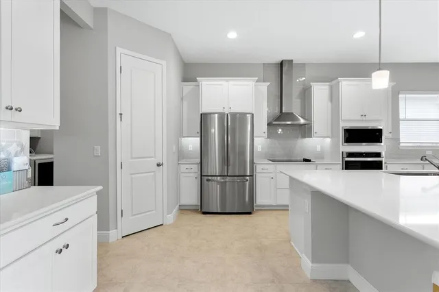 a large white kitchen with a large island oven a stove a sink a couch and a fireplace