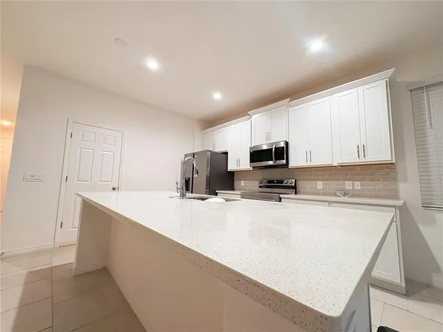 a kitchen with kitchen island a sink a stove a microwave and cabinets