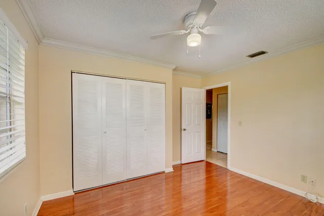 an empty room with wooden floor and ceiling fan