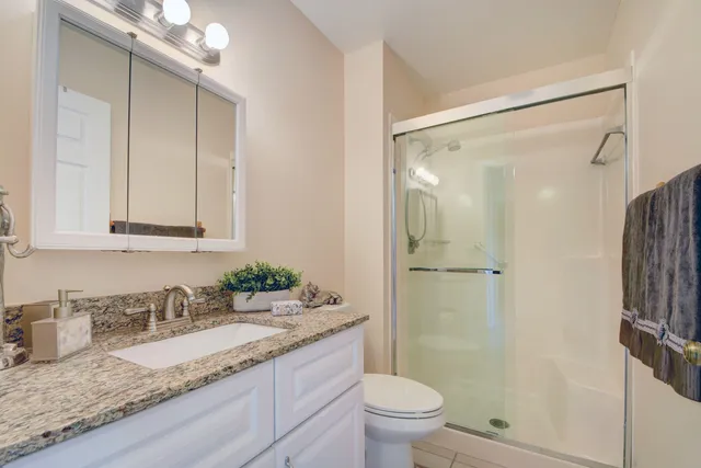 a bathroom with a granite countertop sink toilet and shower