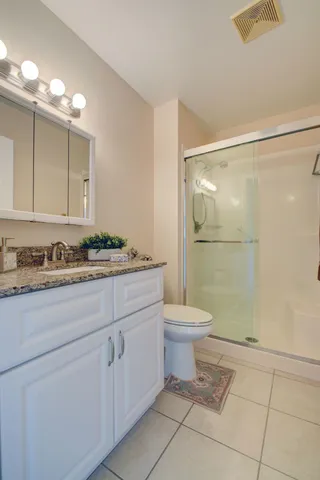 a bathroom with a granite countertop sink a toilet and shower