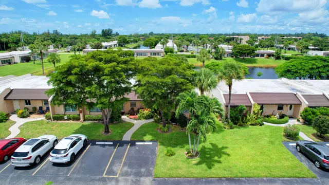 a front view of a building with small garden and palm trees