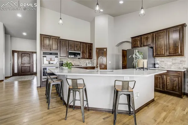 a kitchen with stainless steel appliances kitchen island granite countertop a stove a sink a refrigerator a dining table and chairs