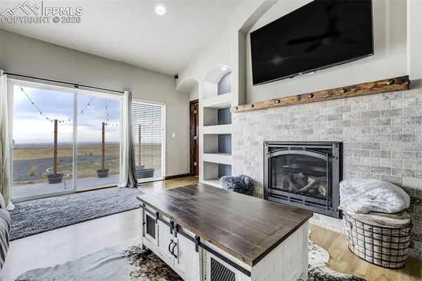 a living room with a fireplace a flat screen tv and view kitchen