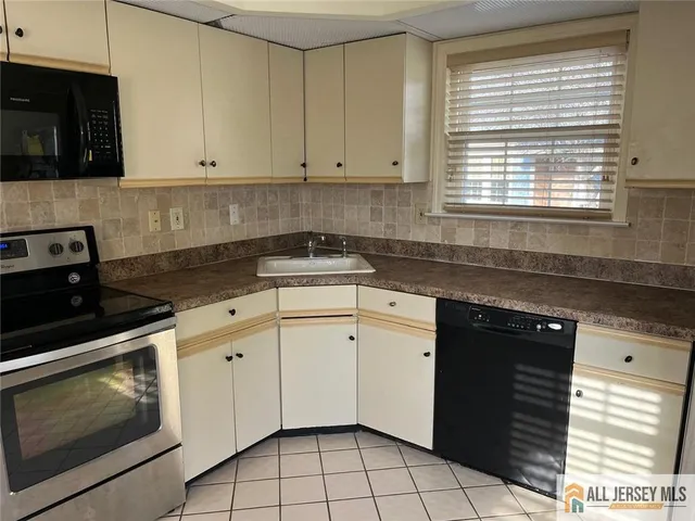 a kitchen with granite countertop white cabinets appliances a sink and a window