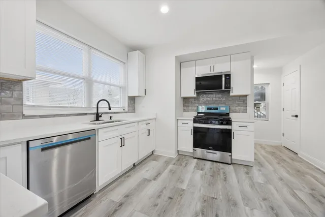 a kitchen with white cabinets and stainless steel appliances