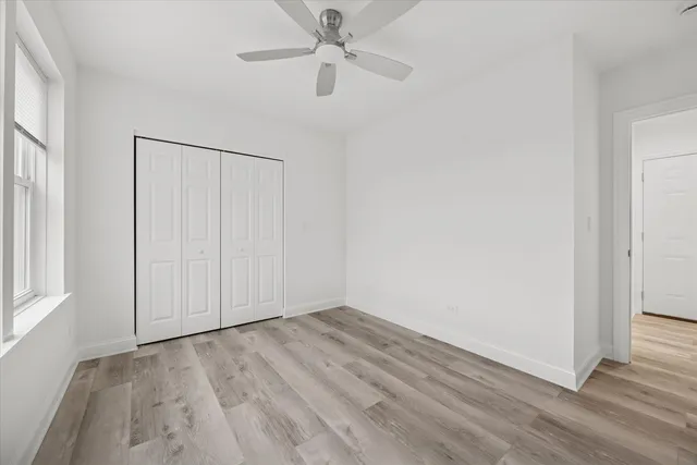 an empty room with wooden floor fan and windows