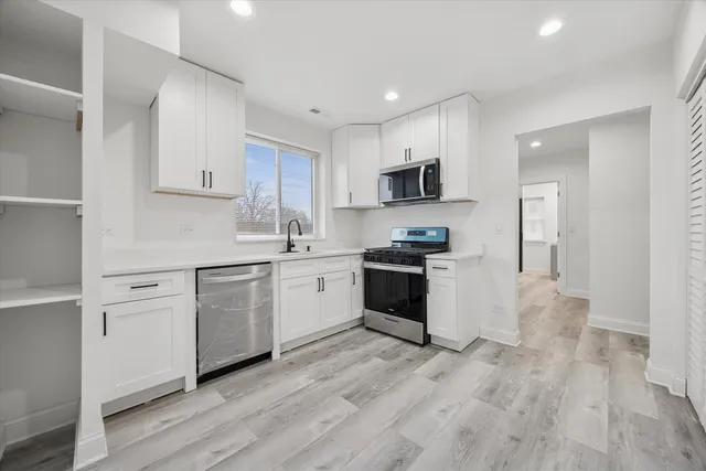 a kitchen with white cabinets and stainless steel appliances