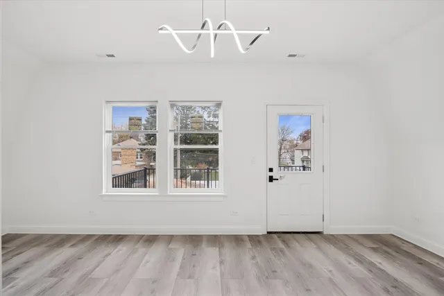 an empty room with wooden floor chandelier fan and windows