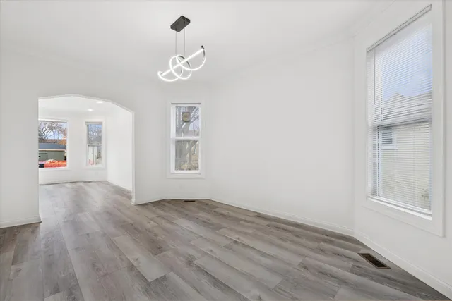 an empty room with wooden floor cabinet and windows
