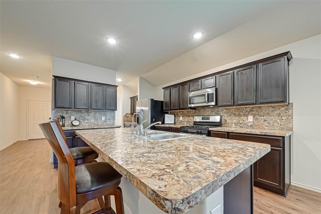 1415 Rodeo Cattle Lane Houston, TX 77049 - Photo 7 of 18 a kitchen with kitchen island granite countertop a sink and stove