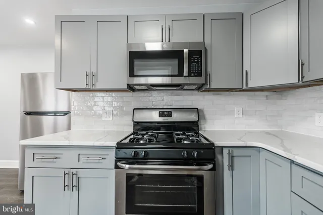 a kitchen with stainless steel appliances granite countertop white cabinets and a stove top oven