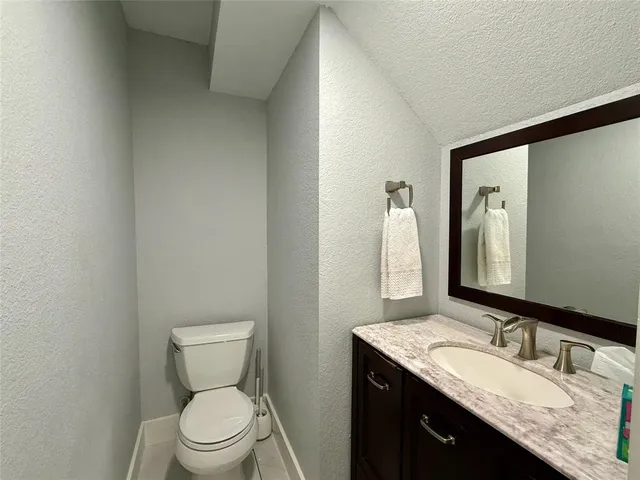 a bathroom with a granite countertop sink toilet and mirror