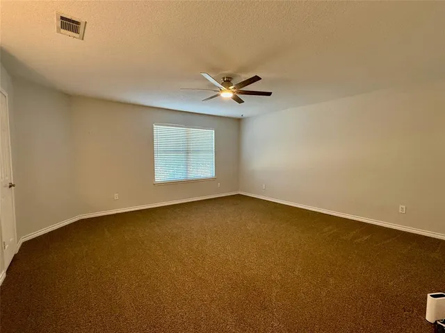 an empty room with a window and a ceiling fan