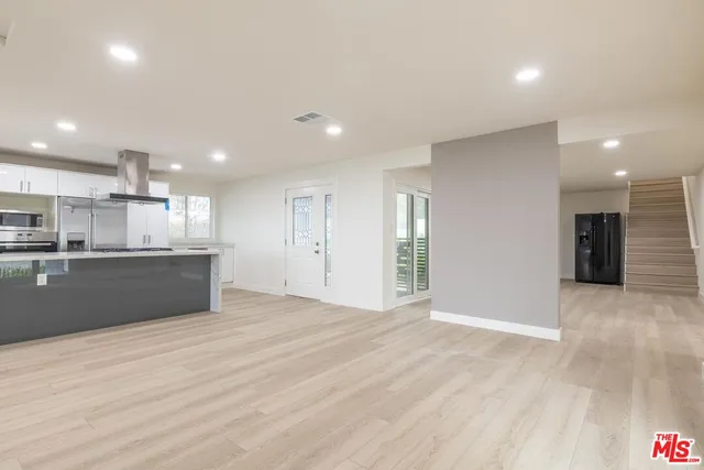 a view of kitchen with kitchen island wooden floor center island and stainless steel appliances