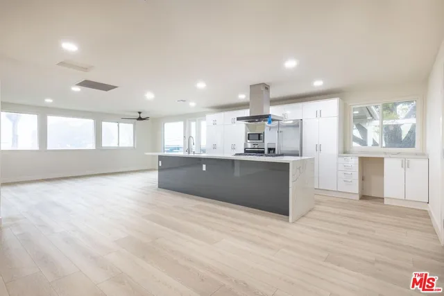 a large kitchen with stainless steel appliances granite countertop a large counter top and a wooden floors