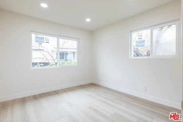 an empty room with wooden floor mirror and windows