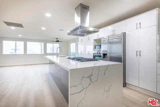 a large kitchen with granite countertop a large counter top a sink appliances and cabinets